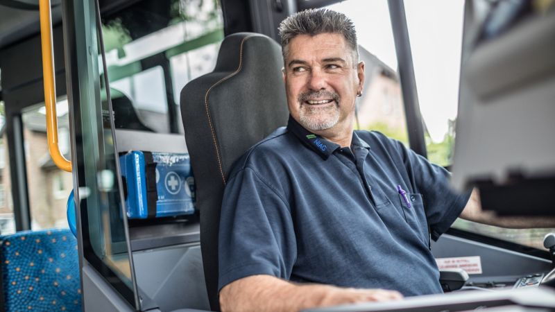 Ein Busfahrer der NIAG am Steuer lächelt