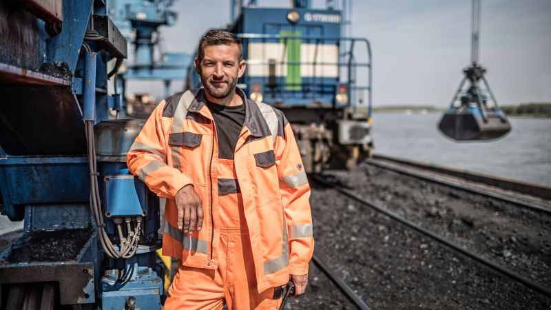 Ein Mitarbeiter im Rheinhafen Orsoy vor einem Güterzug und dem Hafenkran.